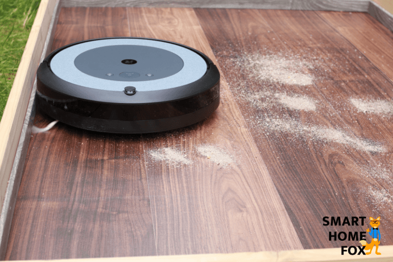 iRobot Roomba i3 Plus reinigt Sand auf einem Laminatboden